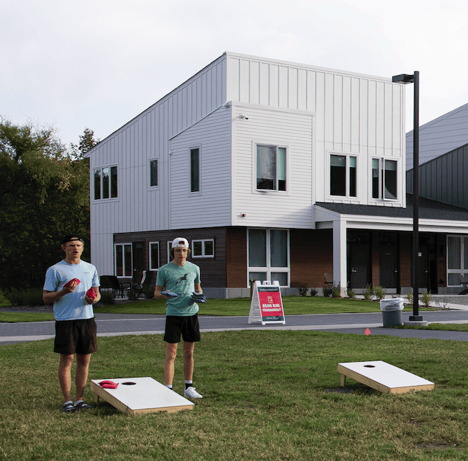 Saint John's Students play corn hole outside their newly-built apartment complex.